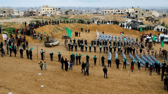 Hamas members dressed in all black, with balaclavas and green headbands, keep guard