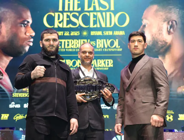 Artur Beterbiev holds up his fist and stands next to Dmitry Bivol