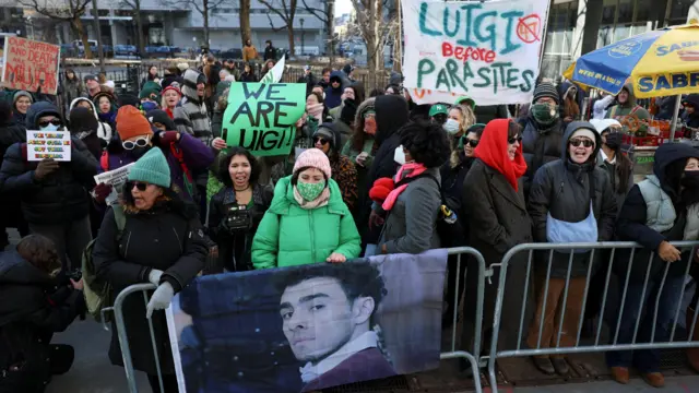 Demonstrators hold placards on the day Luigi Mangione attends a hearing in Manhattan Criminal Court