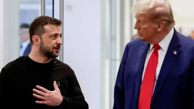 Zelensky and Trump stand side-by-side, with Trump wearing a red tie