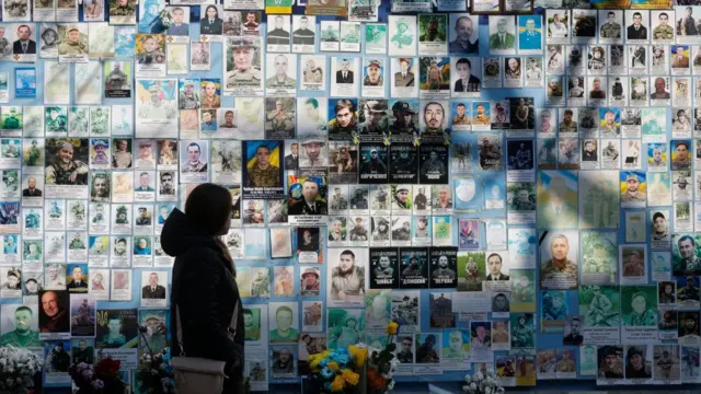 A woman walks past a memorial wall dedicated to fallen defenders of Ukraine in the Russian-Ukrainian war, in downtown Kyiv, Ukraine