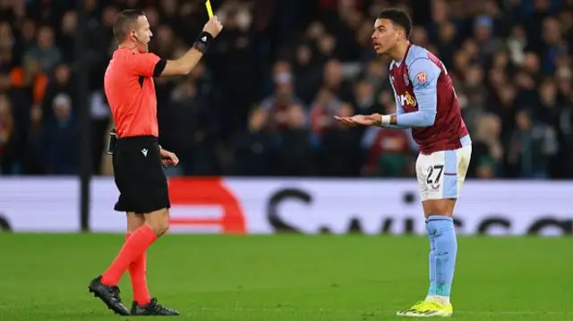 Referee Orel Grinfeeld shows a Yellow card to Morgan Rogers