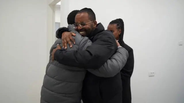 Avera Mengistu hugs his brother, who is smiling, at the initial reception point.