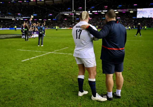 Joe Marler and coach Tom Harrison look on as Scotland celebrate victory in the 2024 Calcutta Cup match