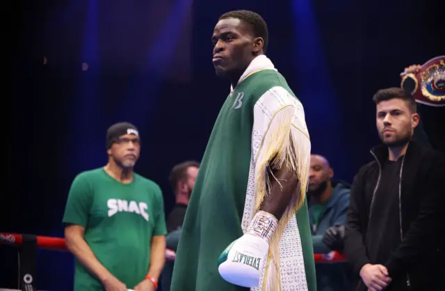 Joshua Buatsi wearing a green robe with gold tassels and boxing gloves