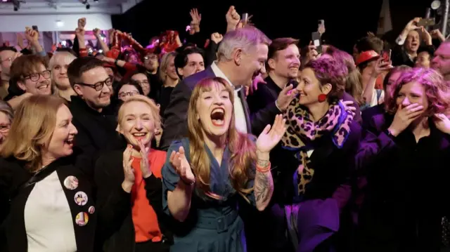 Heidi Reichinnek clapping with enthusiasm, surrounded by supporters and members of Die Linke