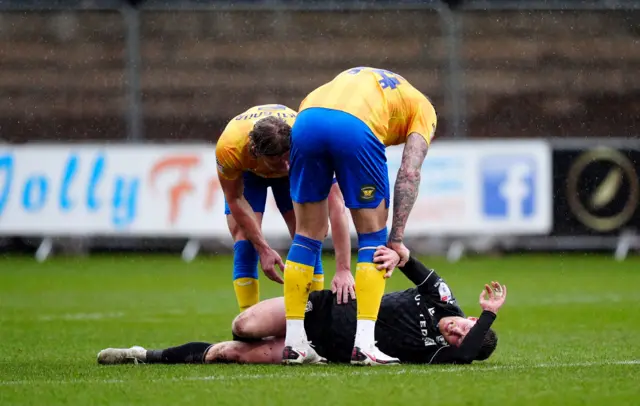 Wrexham's Andy Cannon is attended by two Mansfield players after suffering an injury