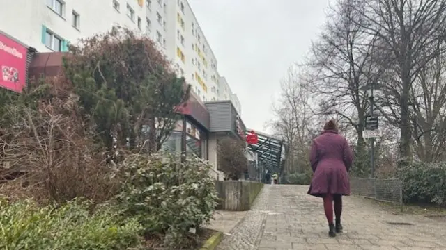 A woman in a purple coat walks up a pavement to a polling station in Berlin