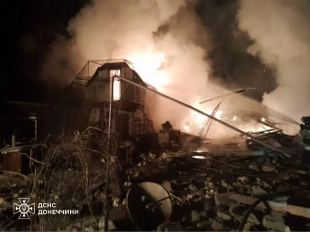 A fire continues to rage in a shelled building surrounded by rubble