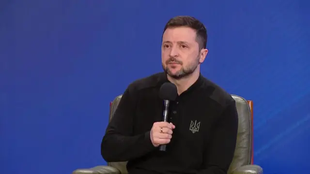 Zelensky speaking into a microphone, wearing a black shirt