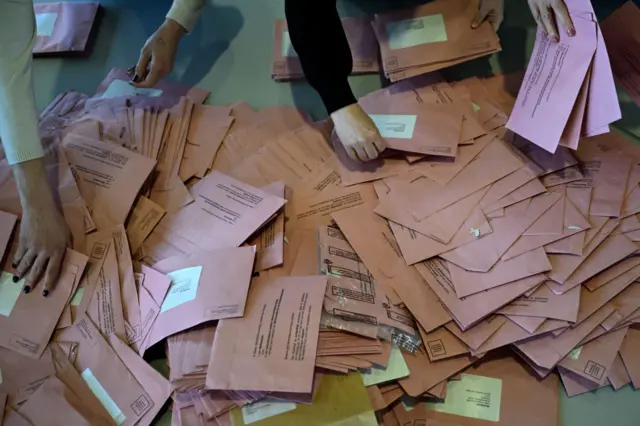 People sort and count ballots in the postal voting centre in Frankfurt am Main, western Germany, on Sunday