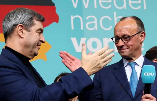 Friedrich Merz and Markus Soeder about to give eachother a handshake