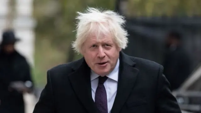 A file photo of Boris Johnson. He is walking down a street in the UK wearing a coat and smart clothing