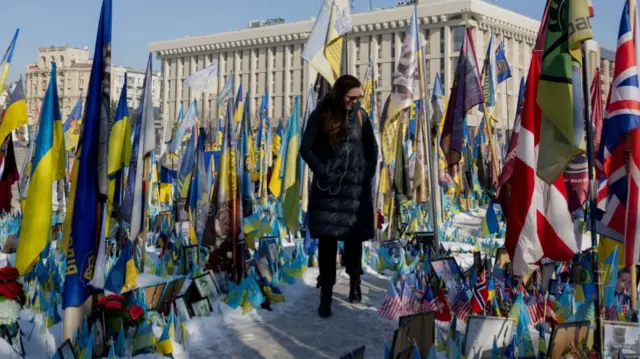 A woman walks at a makeshift memorial for the Ukrainian and foreign fighters at Independence Square in Kyiv