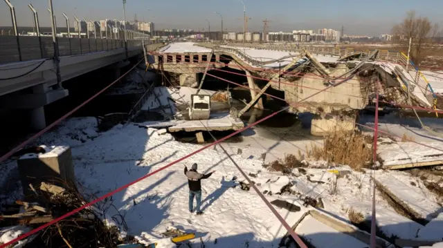 A man looks at the destroyed Romanivka Bridge over the Irpin river