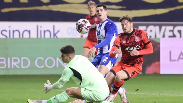 Ben Wiles of Huddersfield Town has his shot cleared off the line by Will Aimson of Wigan Athletic