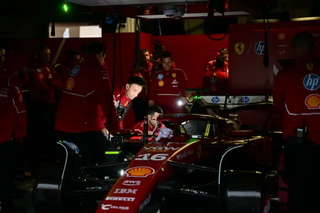 A Ferrari mechanic holds a torch to the cockpit during a power cut