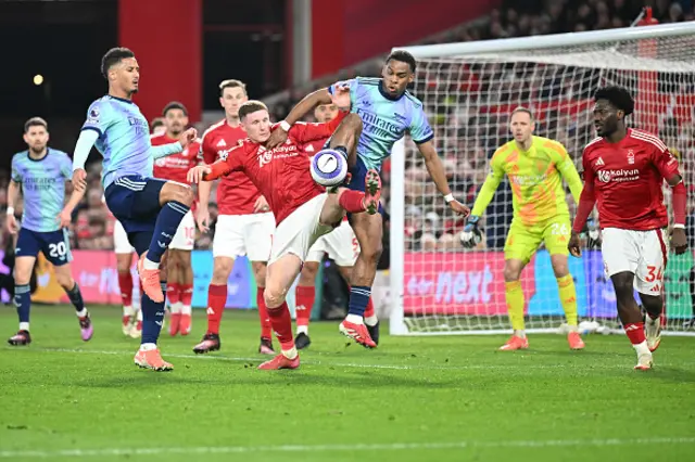 Elliot Anderson of Nottingham Forest is challenged by William Saliba and Jurrien Timber