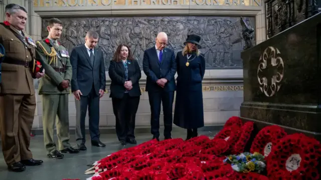 First Minister John Swinney is among the dignitaries who attended the service at the Scottish National War Memorial at Edinburgh Castle. They are standing somberely before hundreds of poppies.