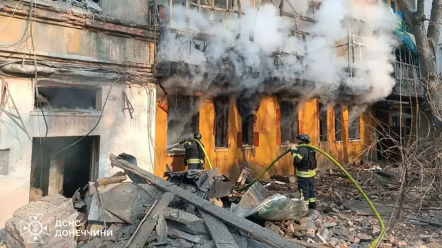 Smoke comes out of windows in a destroyed building