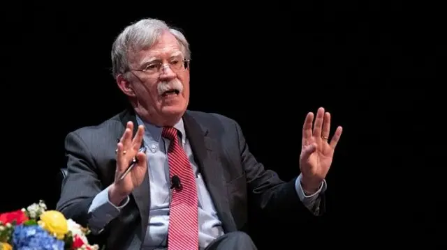 Former National Security Adviser John Bolton speaks on stage while seated.