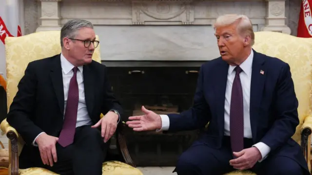 Keir Starmer (L) sitting down in a yellow chair as he speaks to Donald Trump (R) sitting in a matching cahir. Behind them is a marble fireplace