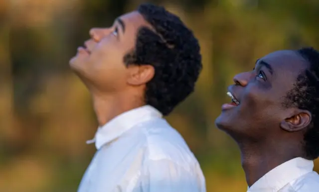 Brandon Wilson and Ethan Herisse looking up to the sky with blurred autumnal colours behind them