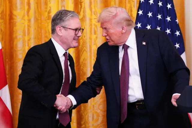 Keir Starmer pulls in Donald Trump's hand during a handshake after a press conference in the East Room at the White House.