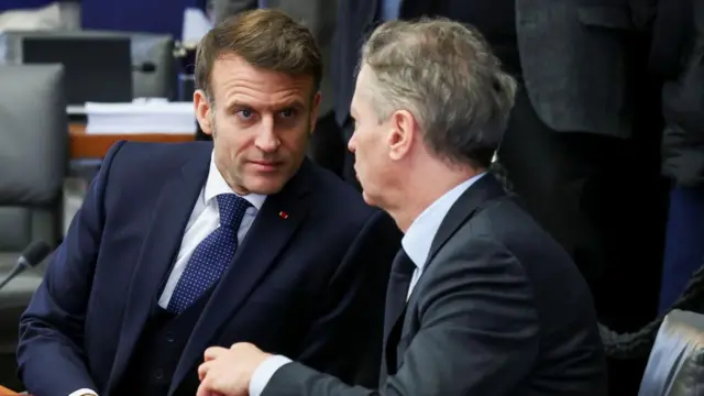 Emmanuel Macron speaking to an individual with his back turned