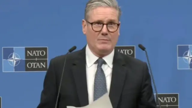 Keir Starmer speaks to reporters in Brussels, standing in front of a blue board bearing the Nato logo