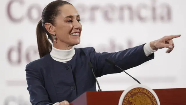 President Claudia Sheinbaum points a finger into the crowd and smiles as she answers questions