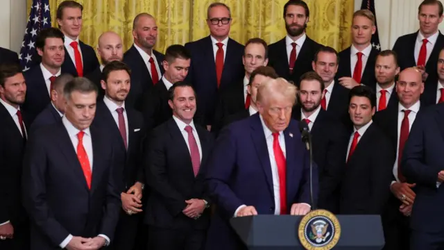 Trump stands in the East Room of the White House with the Florida Panthers ice hockey team in the background