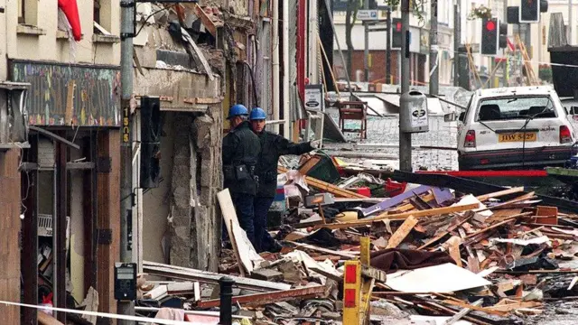 Two men stand in the rubble and aftermath of the 1998 omagh bomb