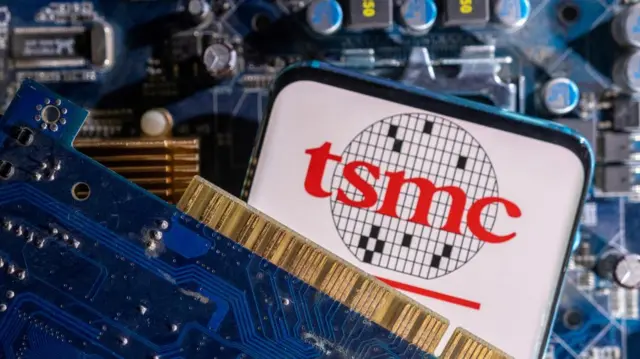 A smartphone with a displayed TSMC (Taiwan Semiconductor Manufacturing Company) logo is placed on a computer motherboard