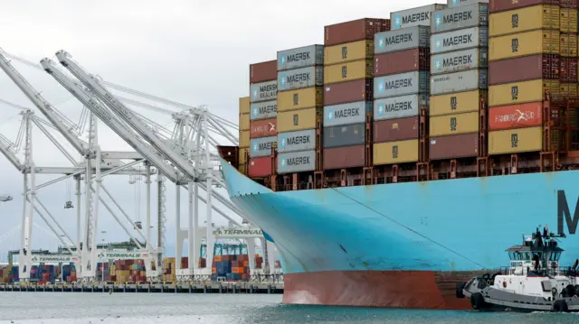 A tugboat guides a container ship at the Port of Oakland in Oakland, California,