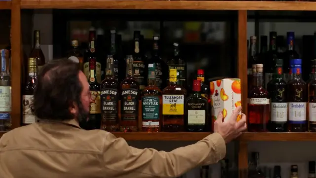 A liquor store worker places a bottle of Diageo's Crown Royal whiskey on a shelf in Los Angeles, California