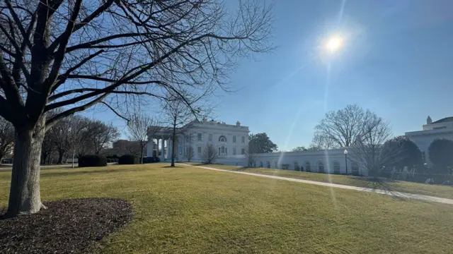 A side angle view of the White House with the sun in the sky