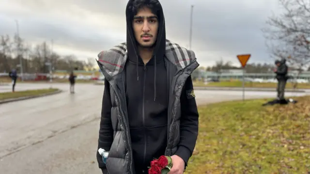 Ismail Moradi holds roses as he talks to the BBC