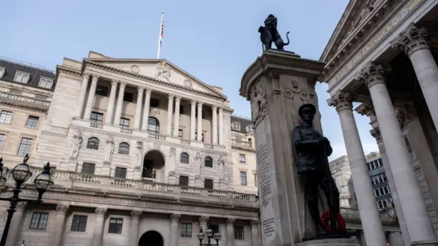 View of the exterior of the Bank of England as taken from the stock exchange building to its right. Bronze statue of WWI soldier placed leaning next to commemorative column