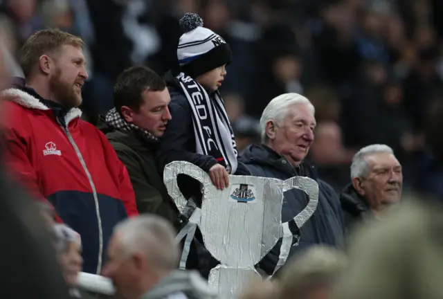 Newcastle fan holds a tinfoil trophy in the stands