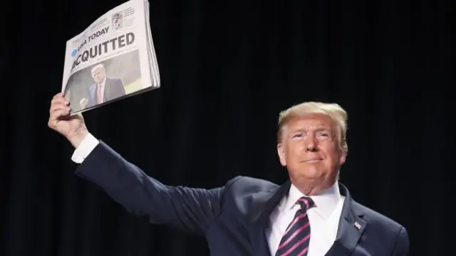 Donald Trump holds newspaper aloft