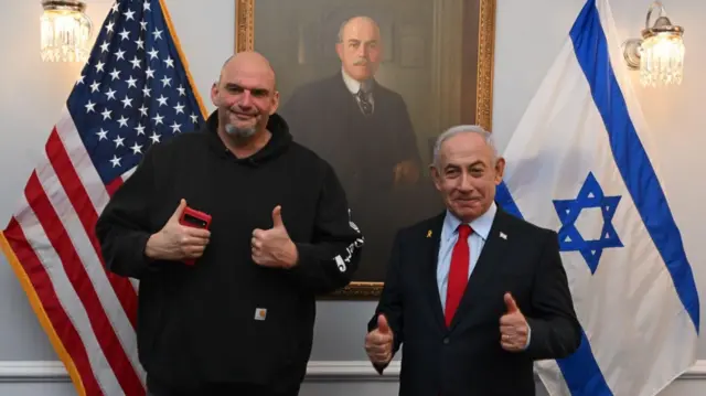 Fetterman and Netanyahu holding both their thumbs up, standing in front of an Israeli flag and an American flag