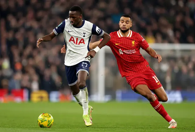 Pape Matar Sarr of Tottenham Hotspur runs with the ball whilst under pressure from Cody Gakpo