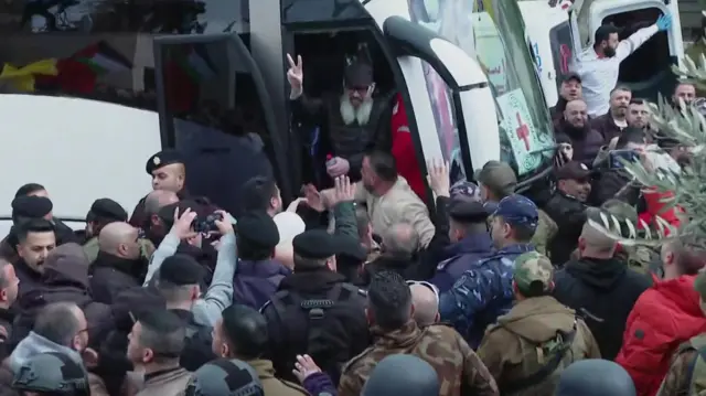 Crowds gather as Palestian prisoners get off a bus.