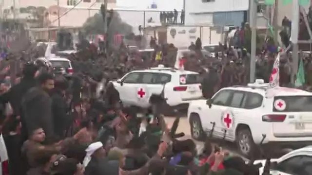 Three Red Cross vehicles driving through a crowd