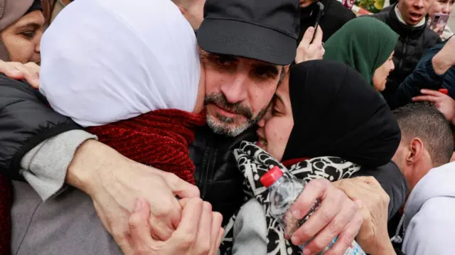 A freed Palestinian prisoner hugs two women as he is greeted after being released from an Israeli jail