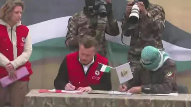 Red Cross workers signing documents with Hamas members