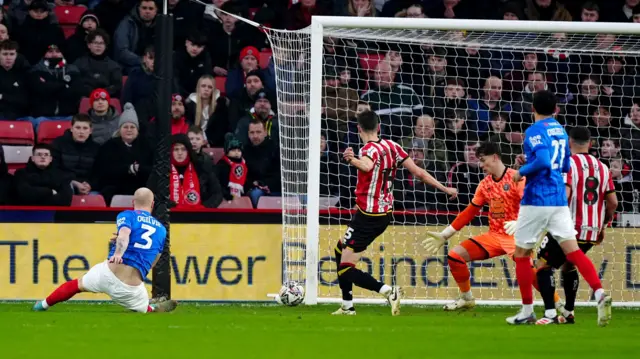 Portsmouth's Connor Ogilvie slides in to score a first-half equaliser at Sheffield United