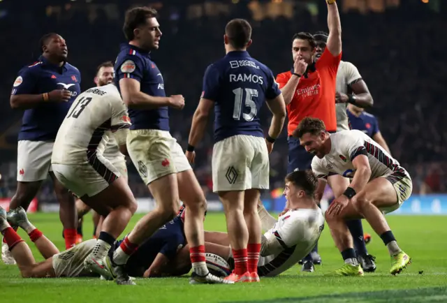 Referee with his hand in the air blowing the whistle for a penalty