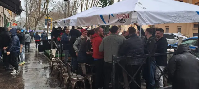 Fans gather under a canopy for rain cover in Rome